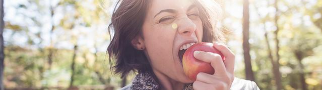 femme qui croque une pomme pour prévenir les caries